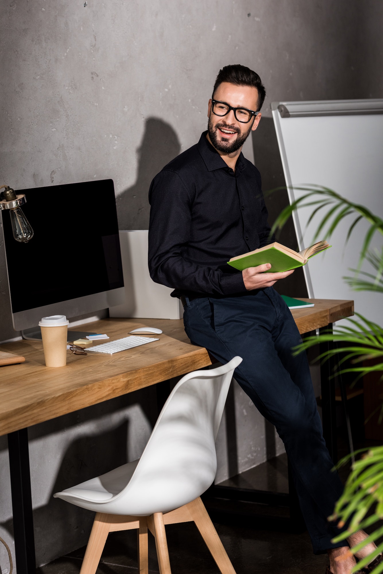 smiling businessman standing with book in office